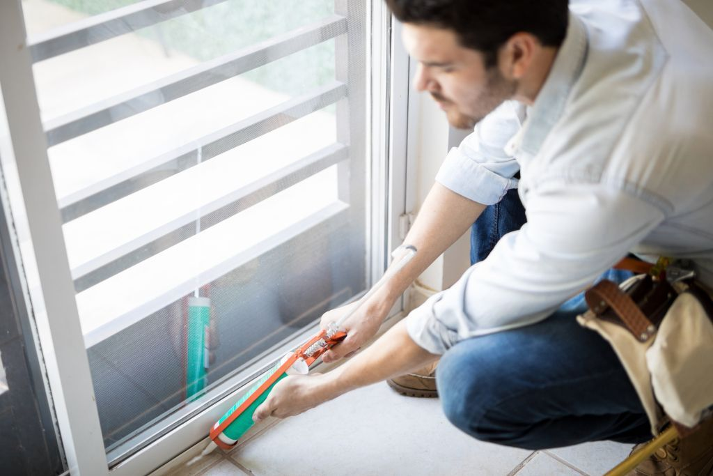 closeup-of-a-young-handyman-applying-some-sealant-on-a-door-with-a-sealing-gun.jpg рабочий